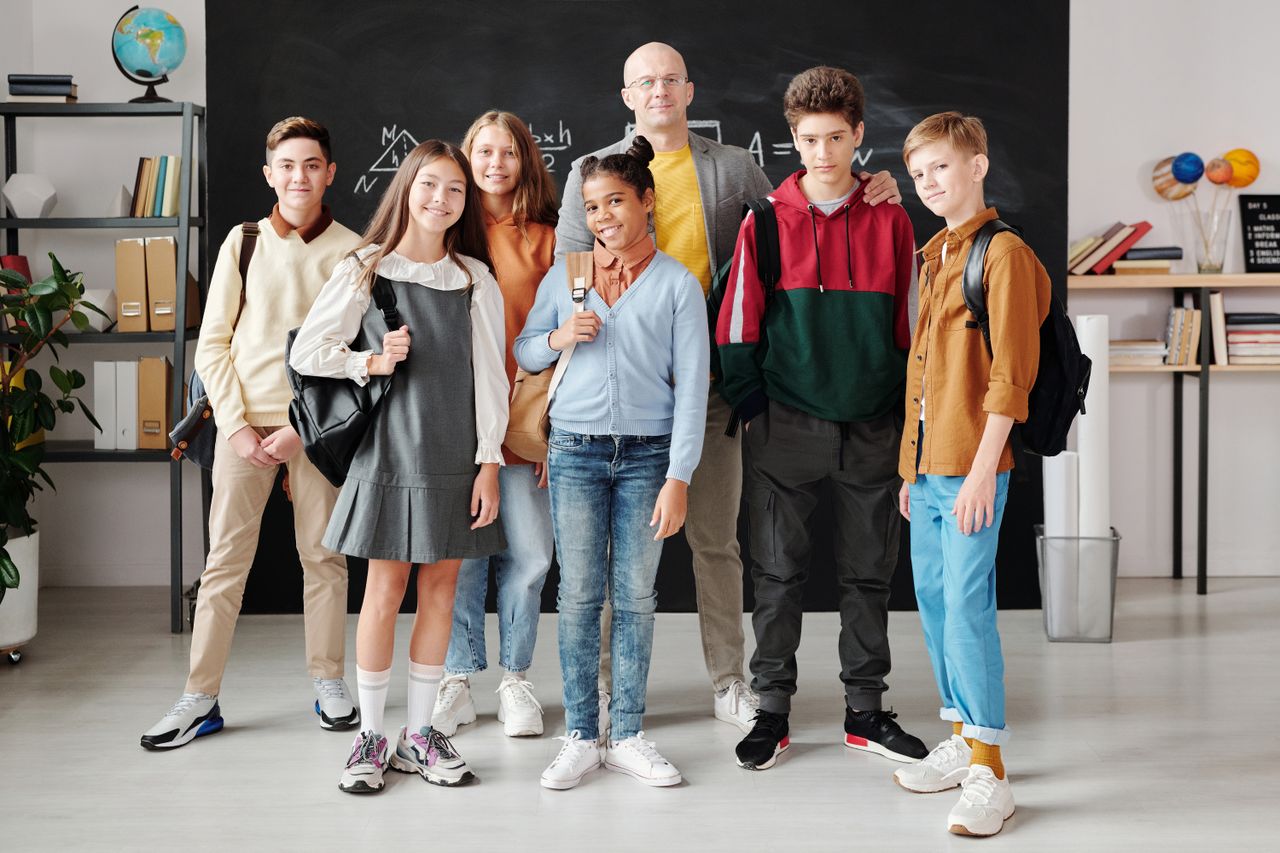 10 things you can learn about themes from WordPress Group of diverse teenagers posing with their teacher in a modern classroom.