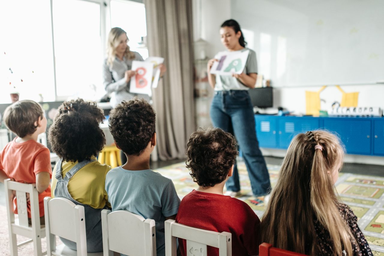 Great things in business are never done by one person Children in a kindergarten classroom engaging with letters during a learning session.